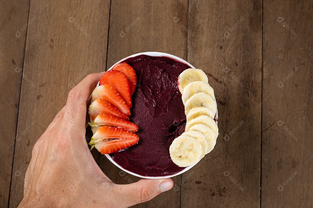 Tigela branca de açaí brasileiro congelado com paçoca, morango e banana.