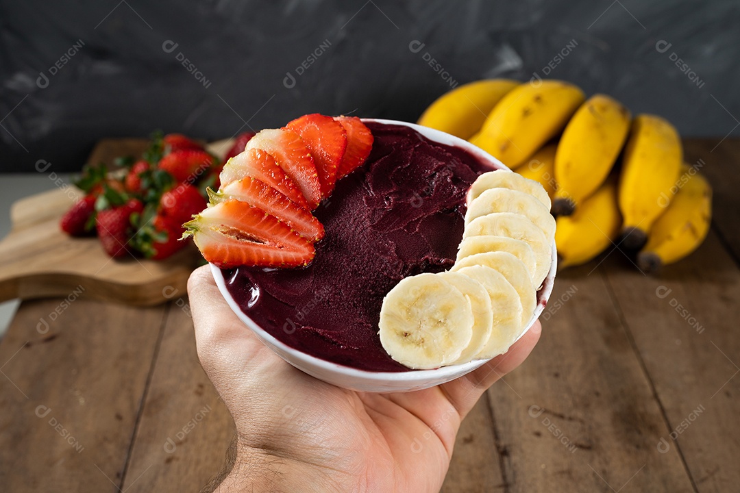 Tigela branca de açaí brasileiro congelado com paçoca, morango e banana.