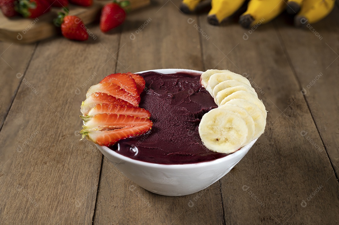 Tigela branca de açaí brasileiro congelado com paçoca, morango e banana.