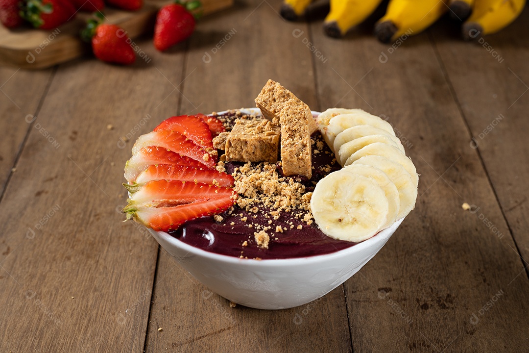 Tigela branca de açaí brasileiro congelado com paçoca, morango e banana.