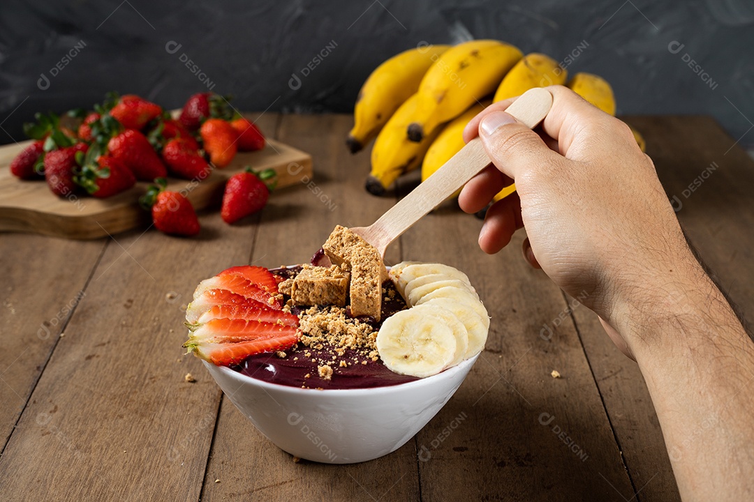 Tigela branca de açaí brasileiro congelado com paçoca, morango e banana.