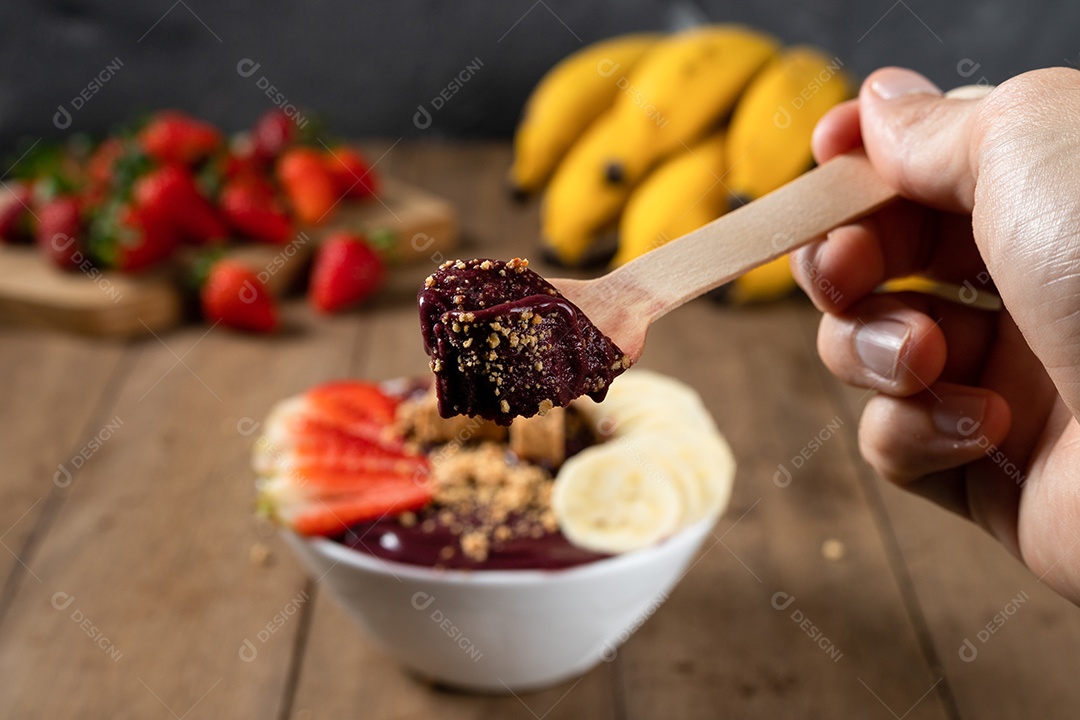 Tigela branca de açaí brasileiro congelado com paçoca, morango e banana.