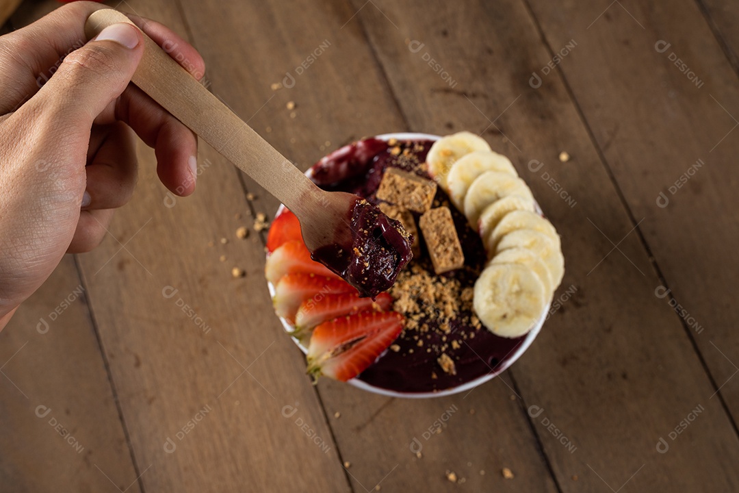 Tigela branca de açaí brasileiro congelado com paçoca, morango e banana.