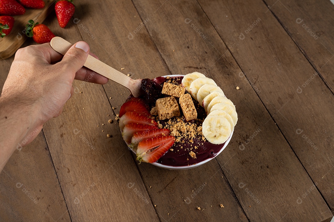 Tigela branca de açaí brasileiro congelado com paçoca, morango e banana.
