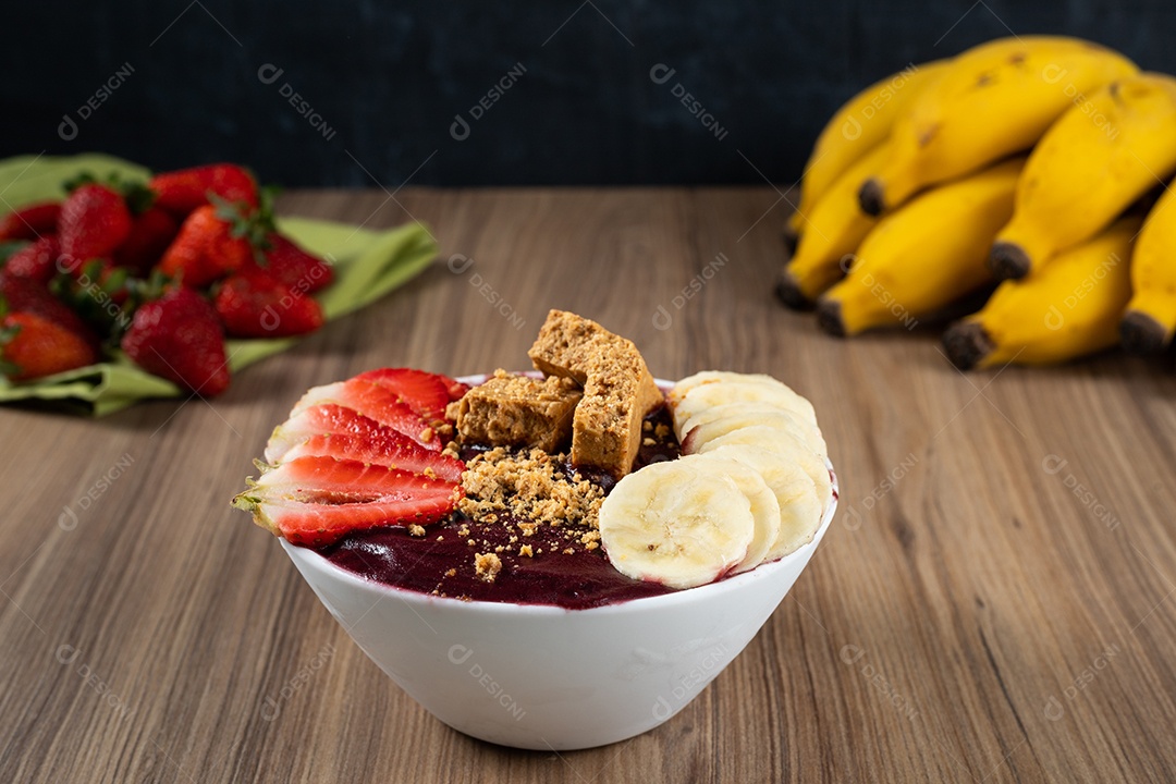 Tigela branca de açaí brasileiro congelado com paçoca, morango e banana.