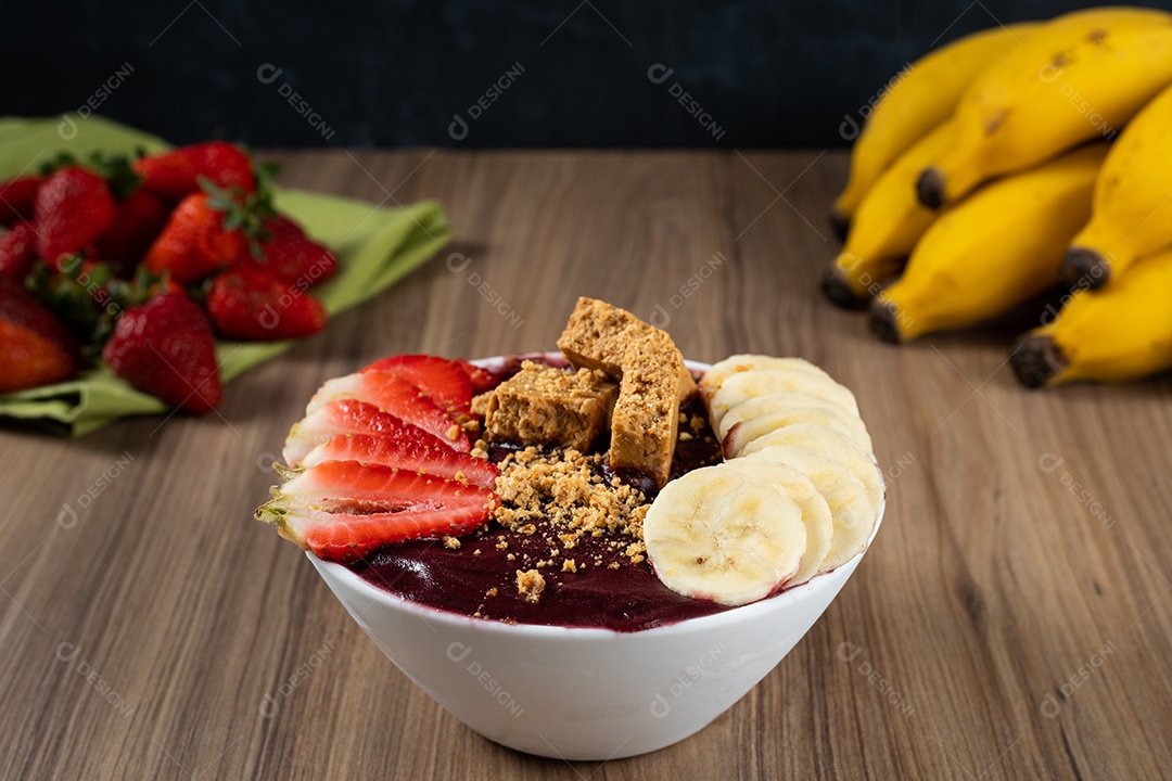 Tigela branca de açaí brasileiro congelado com paçoca, morango e banana.