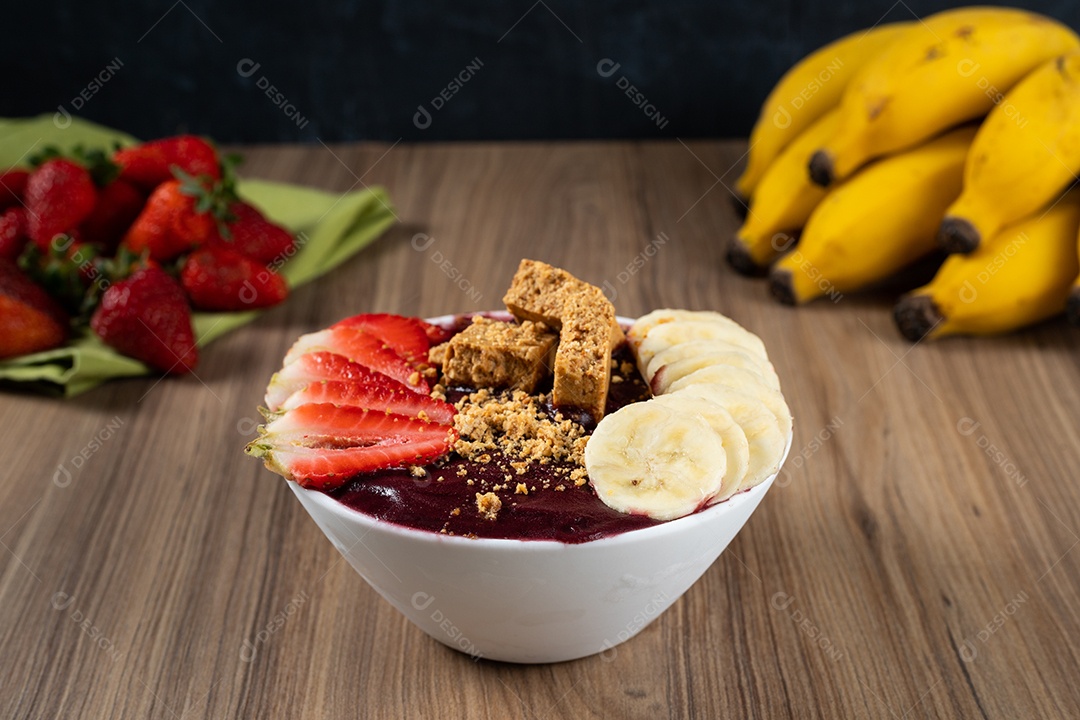 Tigela branca de açaí brasileiro congelado com paçoca, morango e banana.