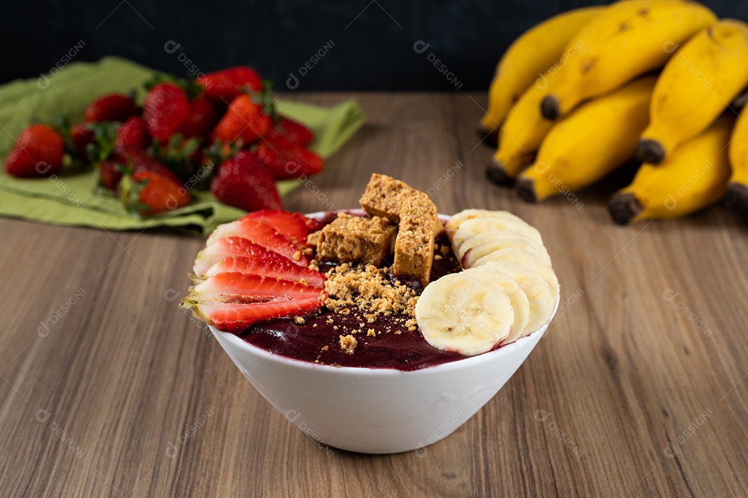 Tigela branca de açaí brasileiro congelado com paçoca, morango e banana.