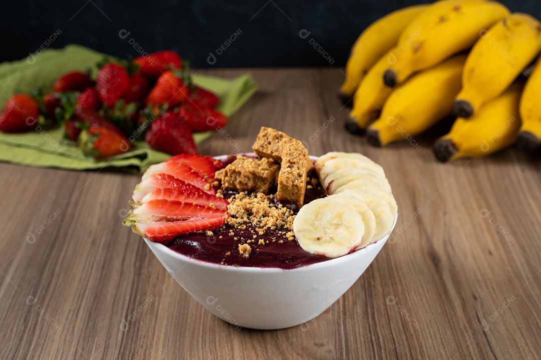 Tigela branca de açaí brasileiro congelado com paçoca, morango e banana.