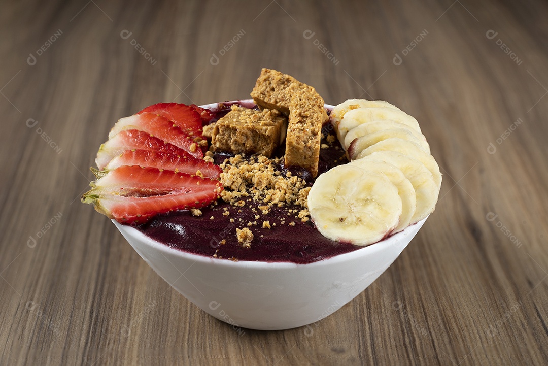 Tigela branca de açaí brasileiro congelado com paçoca, morango e banana.