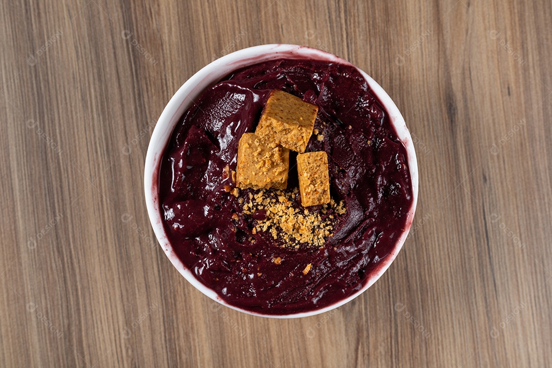 Tigela branca de açaí brasileiro congelado com paçoca, morango e banana.