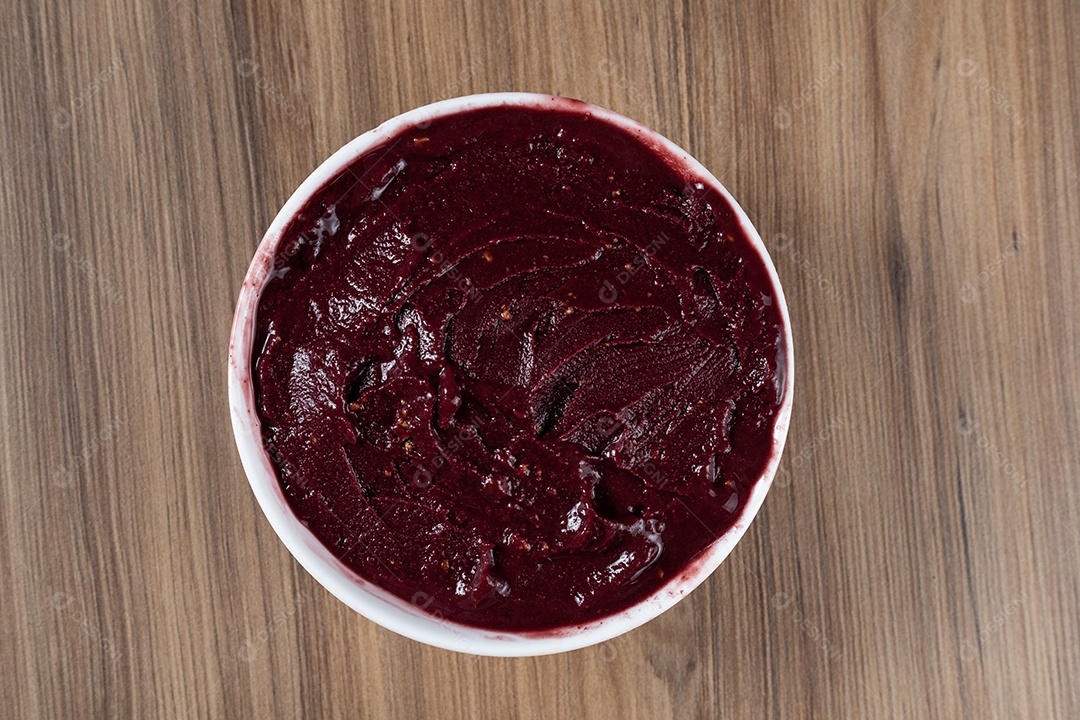 Tigela branca de açaí brasileiro congelado com paçoca, morango e banana.