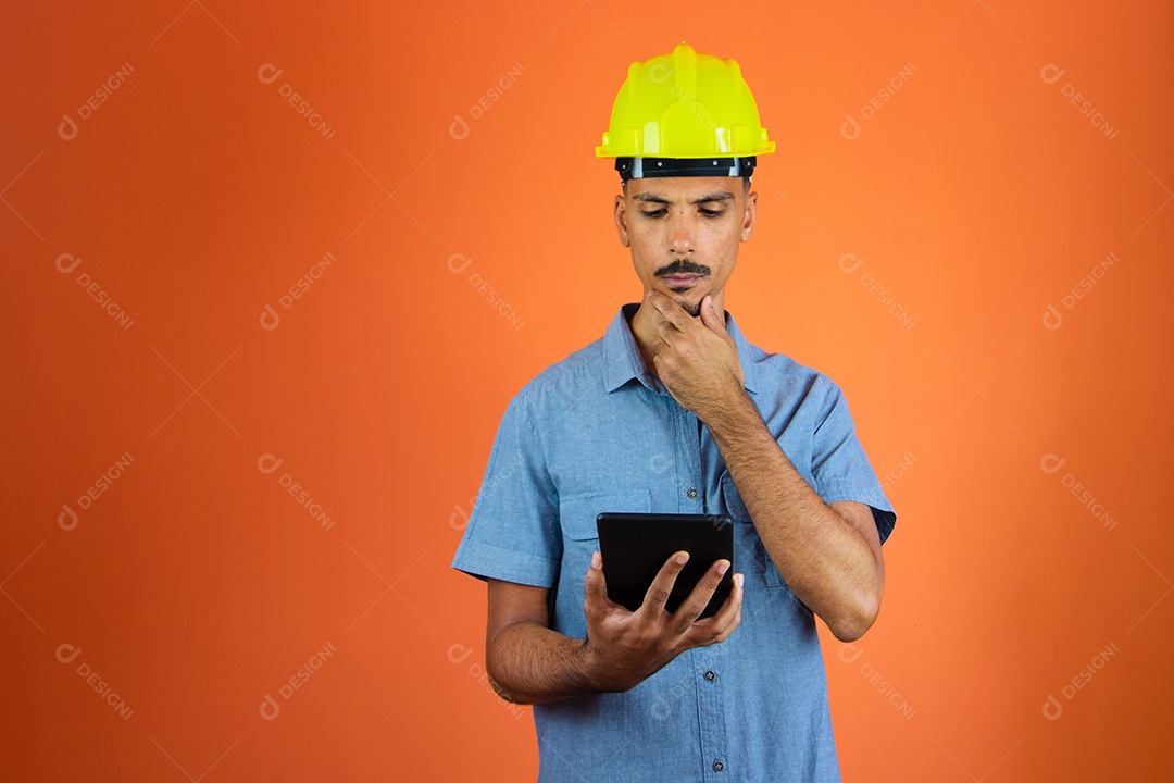 Homem negro no capacete de segurança e camisa azul isolada em laranja.