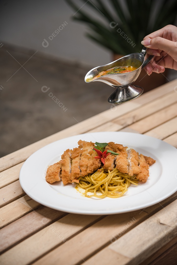 Mãos de pessoa colocando macarronada sobre prato branco mesa madeira