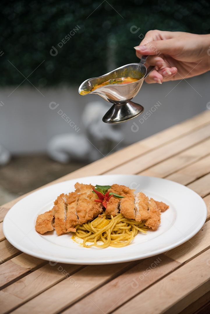 Mãos de pessoa colocando macarronada sobre prato branco mesa madeira