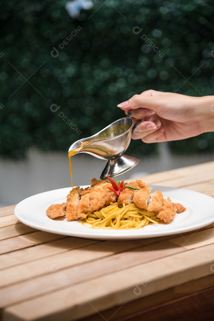 Mãos de pessoa colocando macarronada sobre prato branco mesa madeira