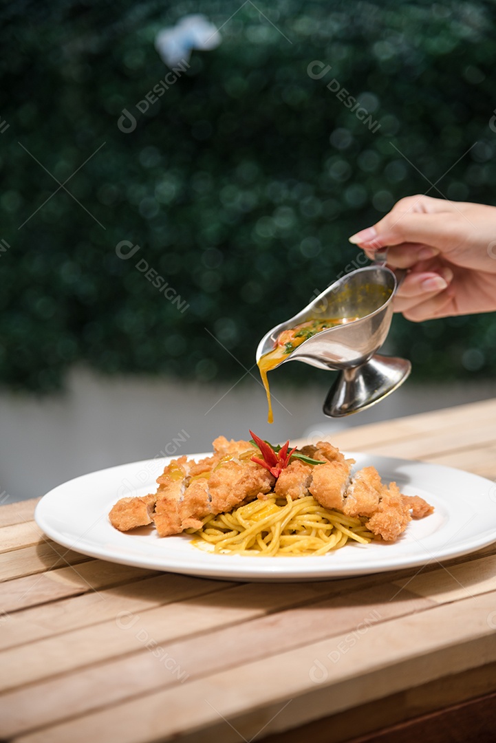 Mãos de pessoa colocando macarronada sobre prato branco mesa madeira