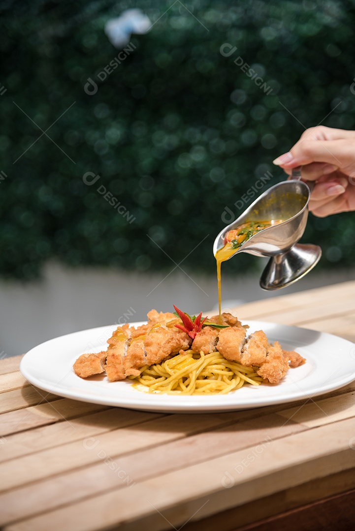 Mãos de pessoa colocando macarronada sobre prato branco mesa madeira