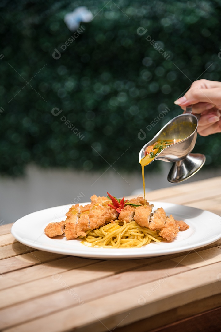Mãos de pessoa colocando macarronada sobre prato branco mesa madeira