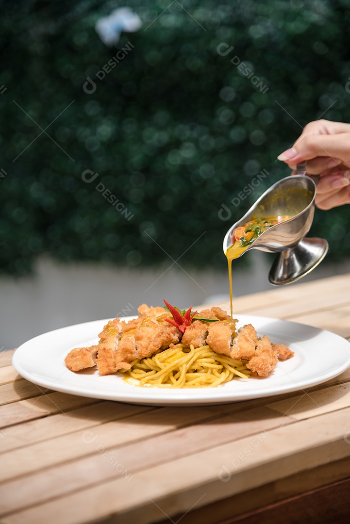 Mãos de pessoa colocando macarronada sobre prato branco mesa madeira