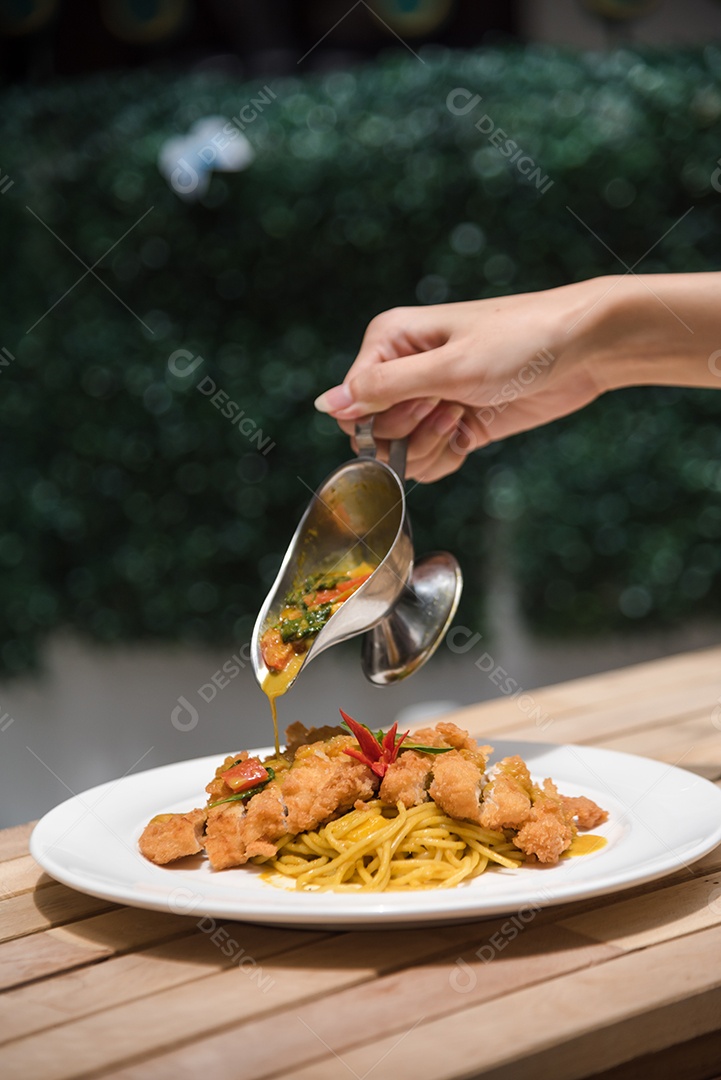 Mãos de pessoa colocando macarronada sobre prato branco mesa madeira