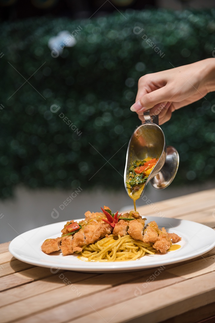 Mãos de pessoa colocando macarronada sobre prato branco mesa madeira