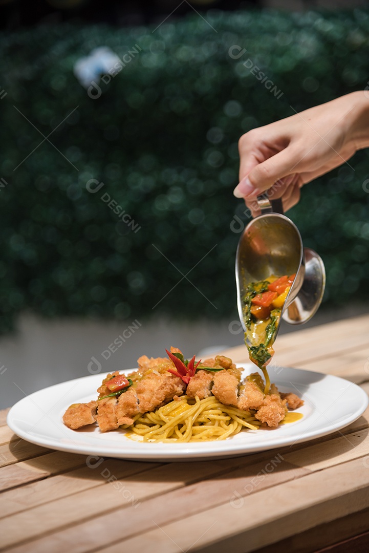 Mãos de pessoa colocando macarronada sobre prato branco mesa madeira