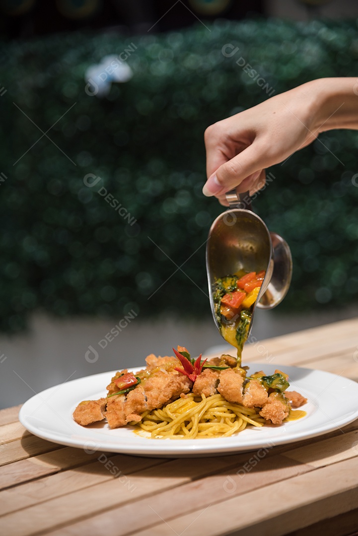 Mãos de pessoa colocando macarronada sobre prato branco mesa madeira