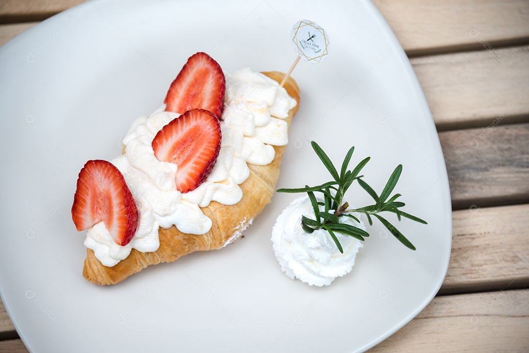Pão sobre prato branco chantily morango cortado em feitas sobre uma mesa madeira