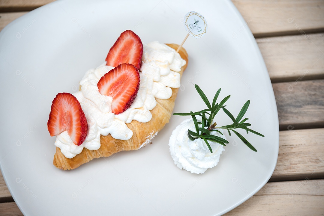 Pão sobre prato branco chantily morango cortado em feitas sobre uma mesa madeira