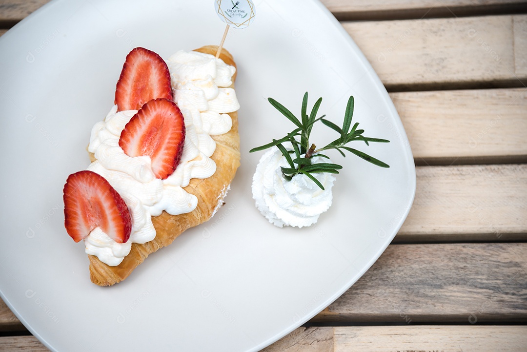 Pão sobre prato branco chantily morango cortado em feitas sobre uma mesa madeira