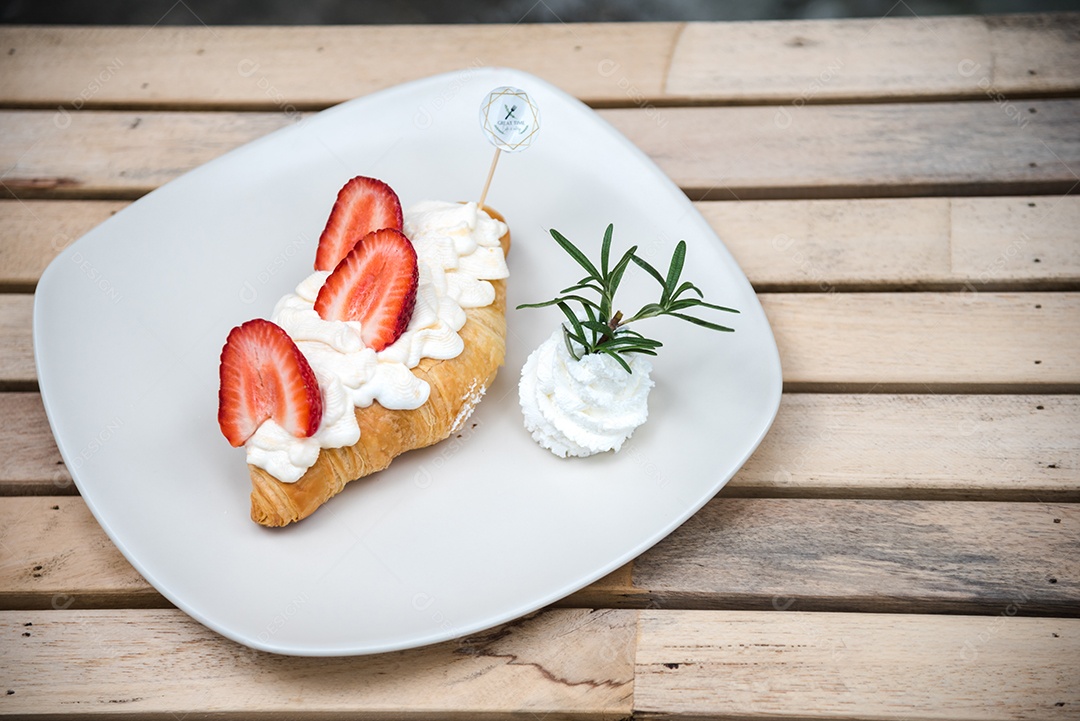 Pão sobre prato branco chantily morango cortado em feitas sobre uma mesa madeira