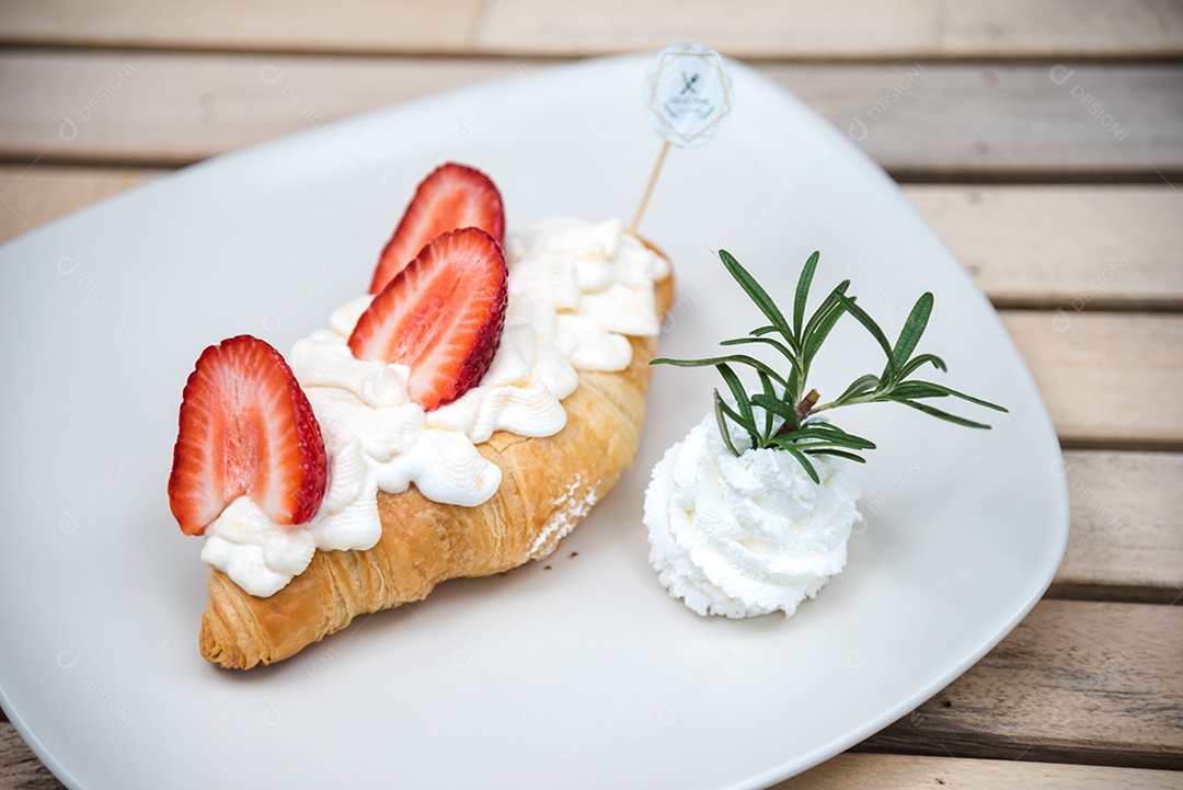 Pão sobre prato branco chantily morango cortado em feitas sobre uma mesa madeira