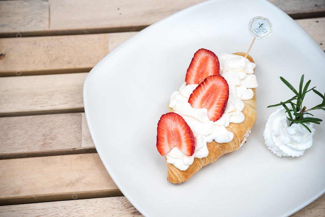 Pão sobre prato branco chantily morango cortado em feitas sobre uma mesa madeira