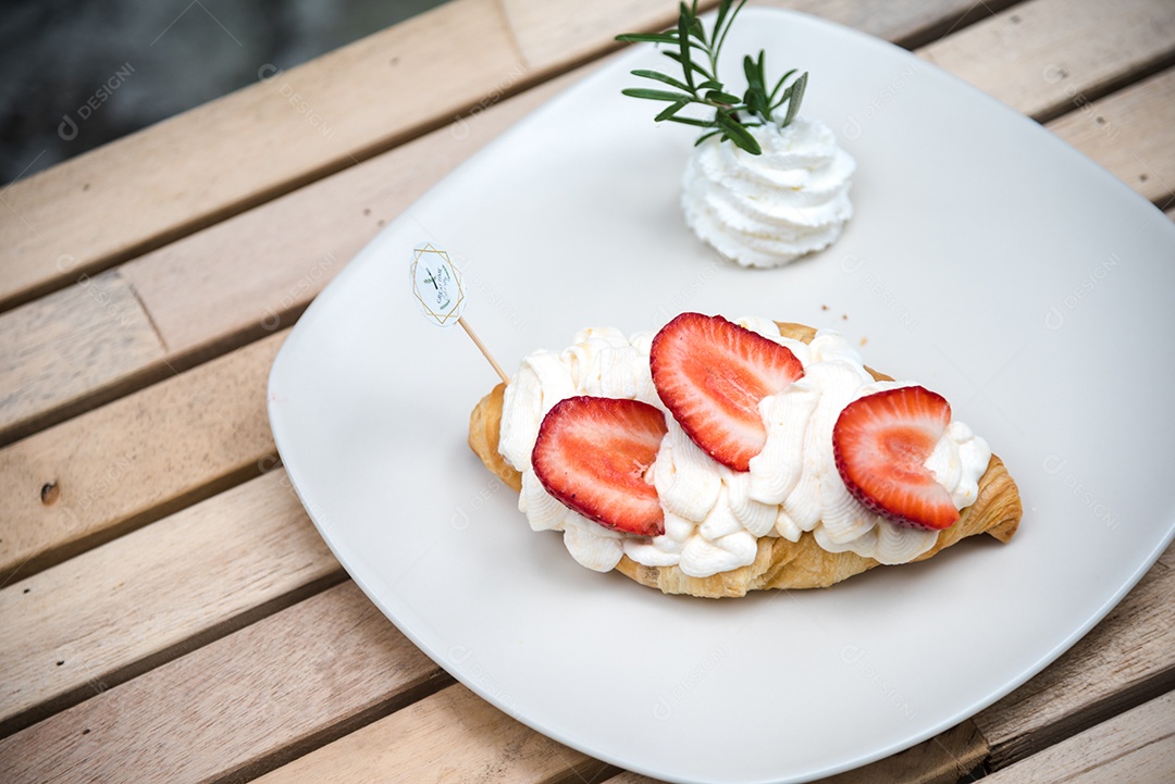 Pão sobre prato branco chantily morango cortado em feitas sobre uma mesa madeira
