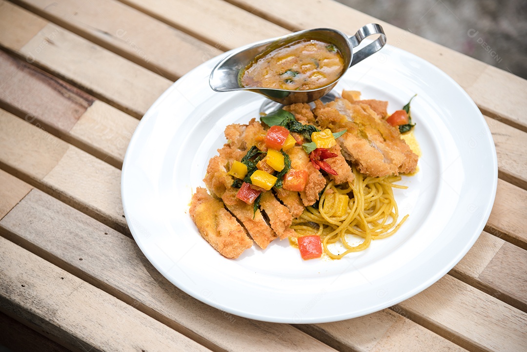 Mãos de pessoa colocando macarronada sobre prato branco mesa madeira