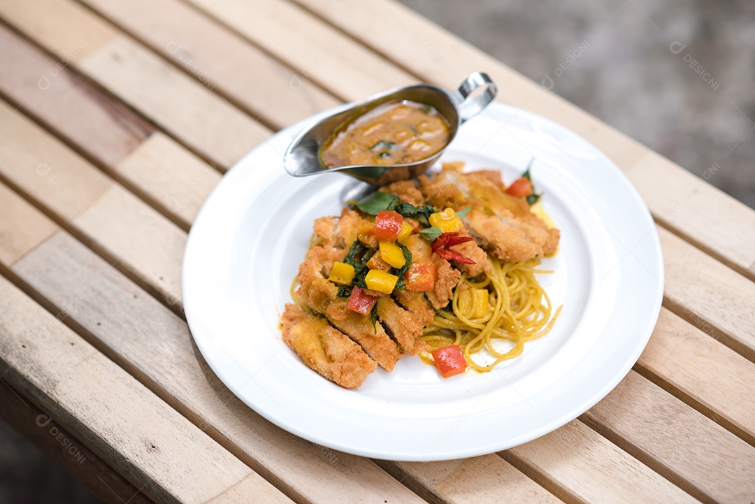 Mãos de pessoa colocando macarronada sobre prato branco mesa madeira
