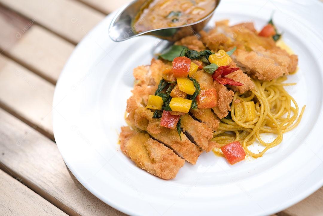 Mãos de pessoa colocando macarronada sobre prato branco mesa madeira