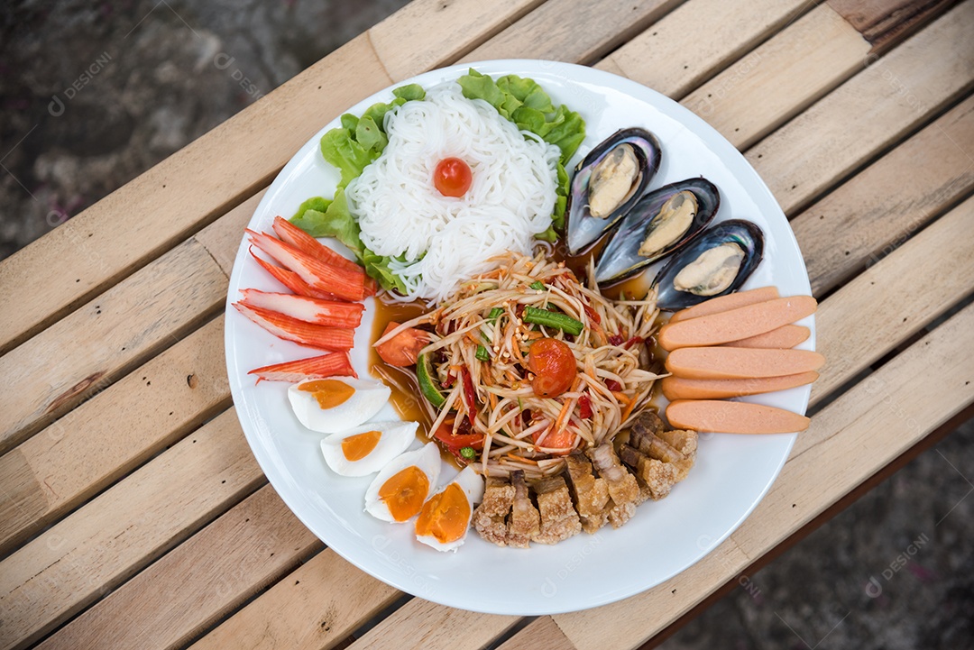 Prato de comida arroz salada legumes torresmo frito sobre uma mesa de madeira