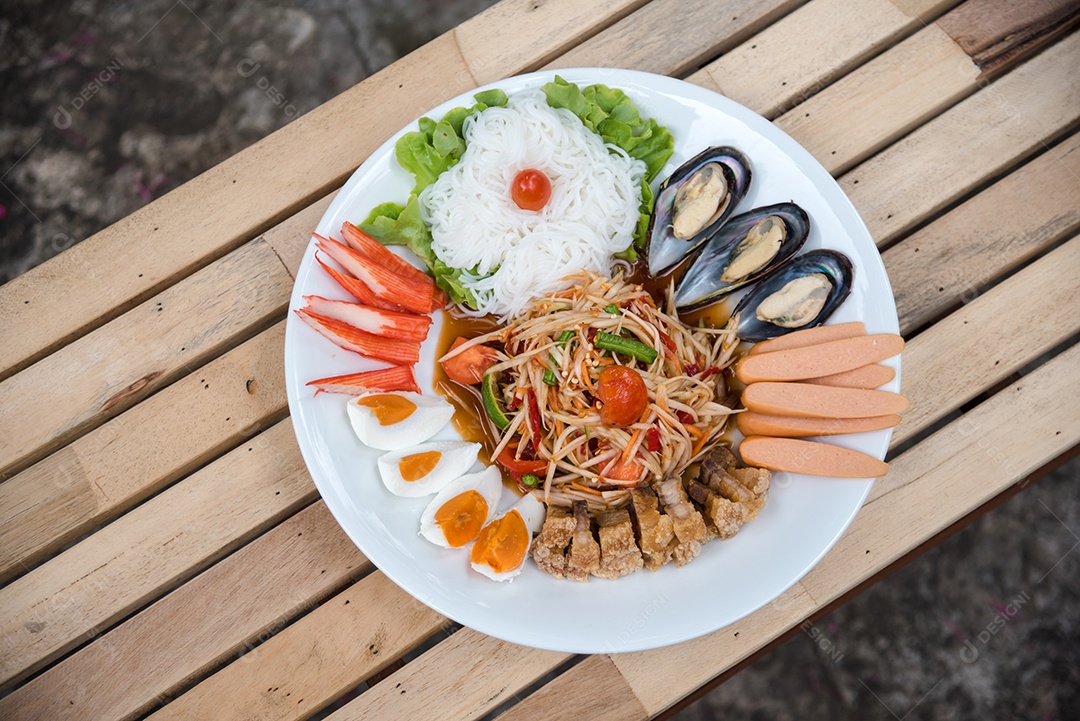 Prato de comida arroz salada legumes torresmo frito sobre uma mesa de madeira