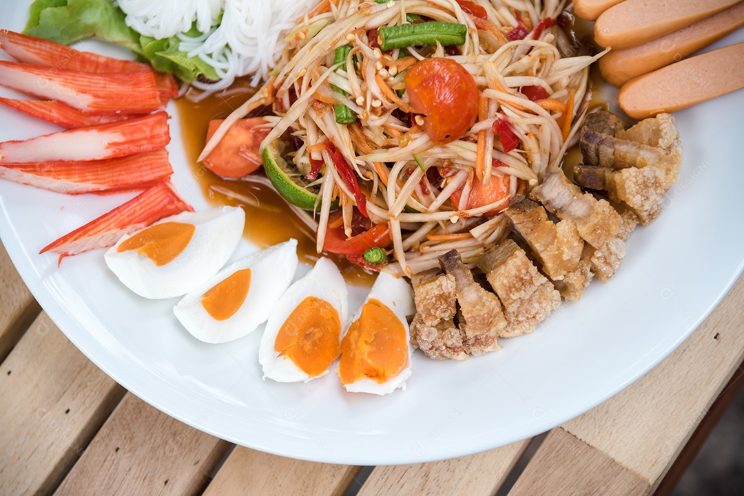 Prato de comida arroz salada legumes torresmo frito sobre uma mesa de madeira