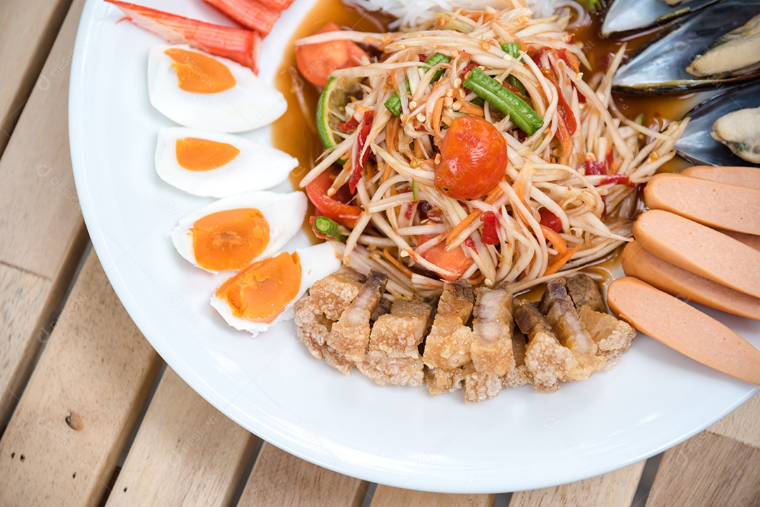 Prato de comida arroz salada legumes torresmo frito sobre uma mesa de madeira