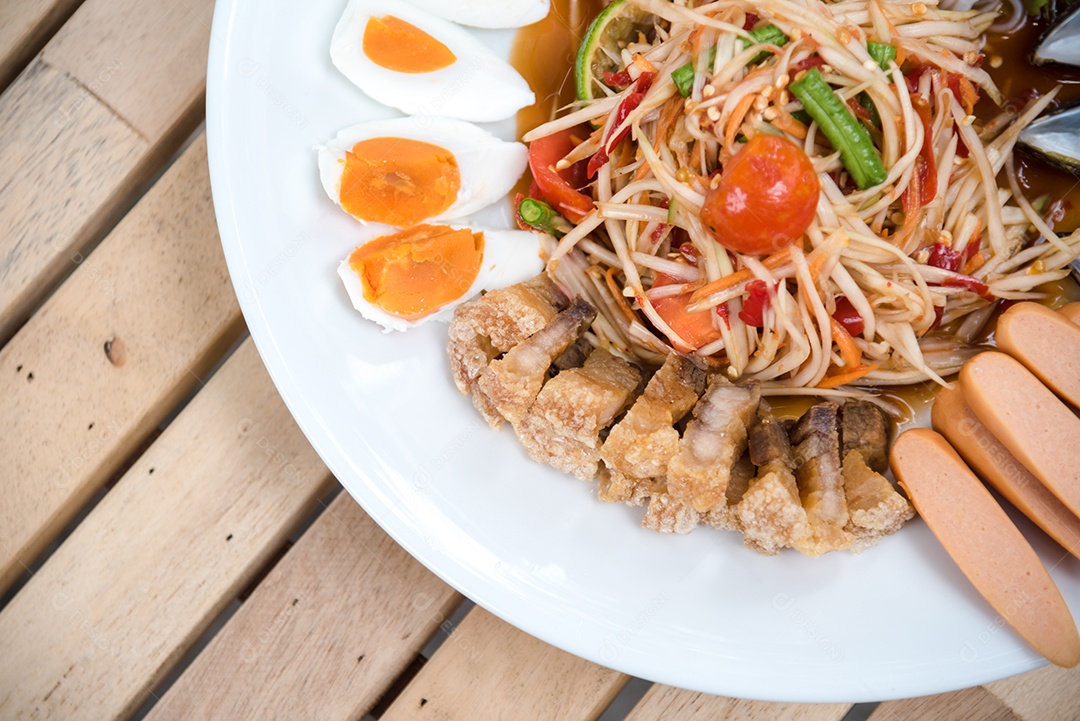 Prato de comida arroz salada legumes torresmo frito sobre uma mesa de madeira