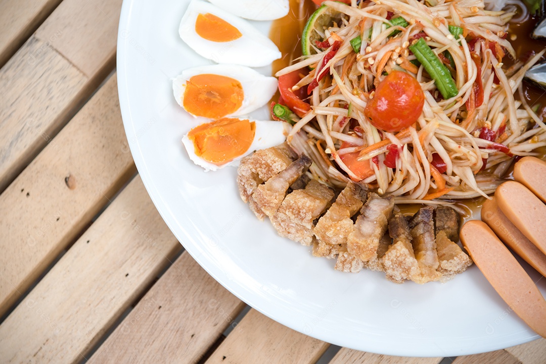 Prato de comida arroz salada legumes torresmo frito sobre uma mesa de madeira