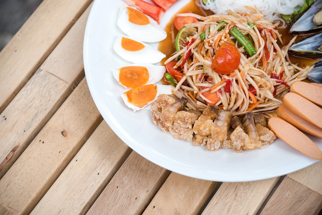 Prato de comida arroz salada legumes torresmo frito sobre uma mesa de madeira