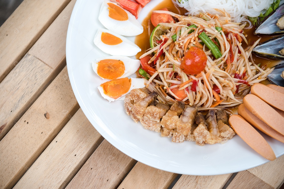 Prato de comida arroz salada legumes torresmo frito sobre uma mesa de madeira