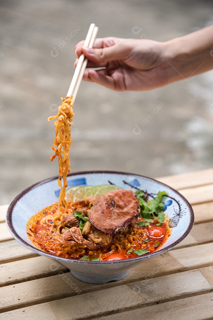 Yakisoba sobre uma tigela Mãos de pessoa pegando com Hashi