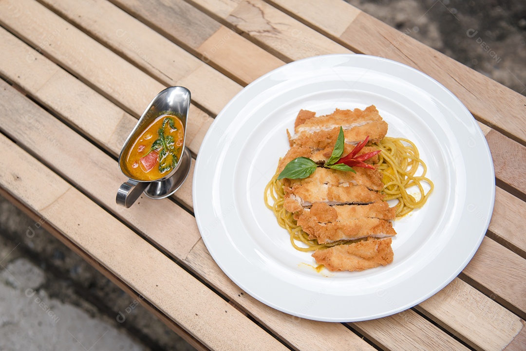 Prato de macarronada sobre prato branco mesa madeira