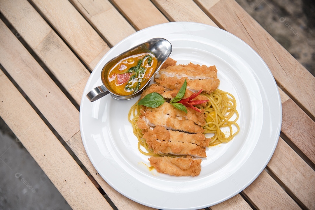 Person's hands putting pasta on a white plate on a wooden table