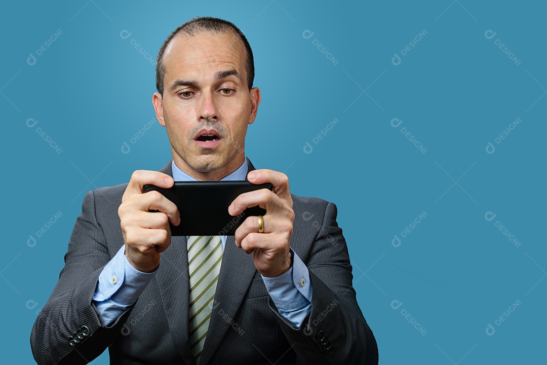 Homem maduro de terno e gravata, jogando em seu smartphone